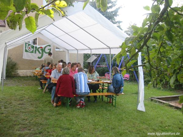 Die Gäste sitzen an Biertischgarnituren unter dem großen Pavillon, an der hinteren Wand hängt das KjG-Banner