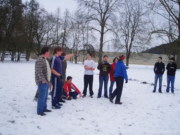 Jugendliche stehen auf einem verschneiten Fußballplatz