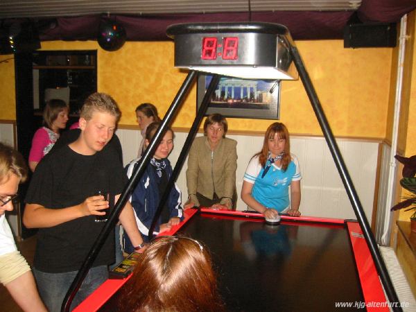 Jugendliche beim Air-Hockey spielen (vielleicht als Mischung aus Ping-Pong und Eishockey zu beschreiben)