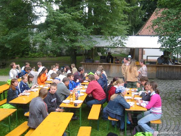 Weißwurst- und Wienerle-Frühstück an der Rundkapelle. Die Gäste sitzen an Biertischen, das Essen wird an einer Holzbude ausgegeben