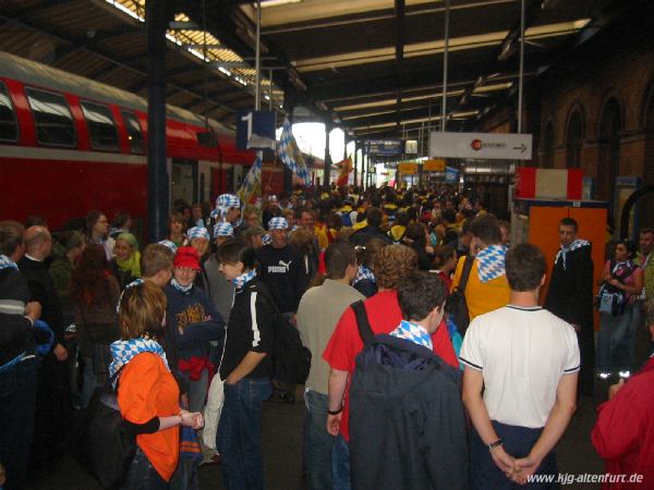 Ankunft auf einem überfüllten Bahnsteig am Bonner Bahnhof. Alle Teilnehmer unserer Gruppe tragen blau-weiße Hals-/Kopftücher, zusätzlich haben wir zwei große Bayern-Fahnen dabei