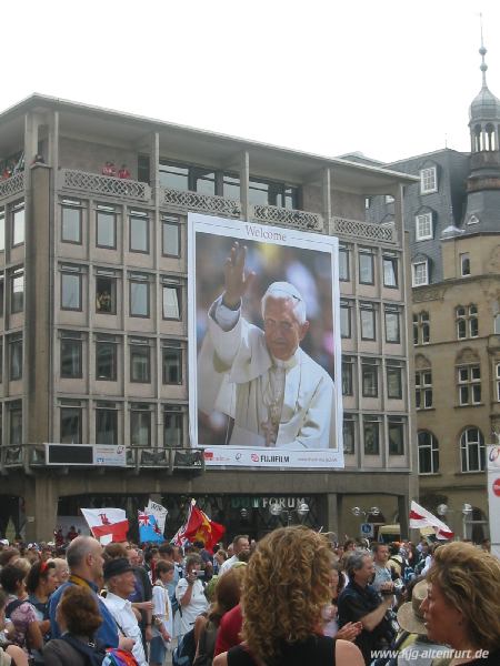 Ein riesiges Portrait von Papst Benedikt XVI an einer Hauswand gegenüber des Doms