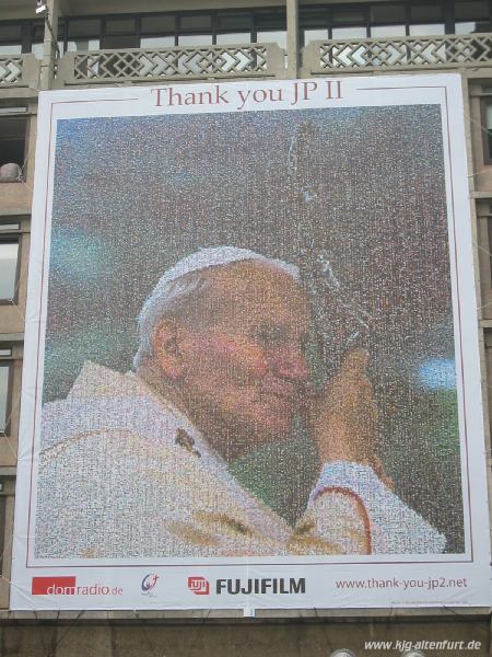 Ein riesiges Portrait von Papst Johannes Paul II an einer Hauswand gegenüber des Doms. Das Protrait ist ein Mosaik aus tausenden kleinen Fotos, die Pilger aus aller Welt eingeschickt haben
