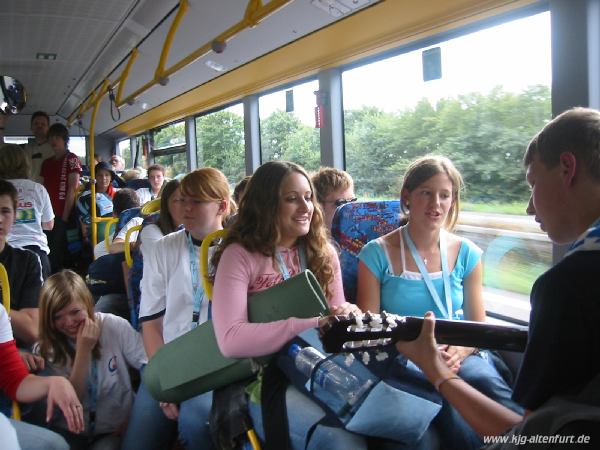 Wir sitzen mit anderen Jugendlichen im Shuttle-Bus vom Bahnhof Köln zum Marienfeld, Thomas spielt Gitarre