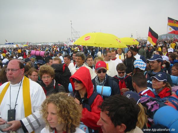 Die Pilger bei der Hauptmesse auf dem Marienfeld, die Kommunionausteiler standen unter gelben Schirmen