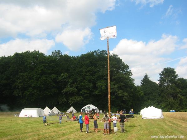 Der Fahnenmast steht, im Hintergrund das Lager mit neun großen, weißen Zelten und einem rießen Pavillon