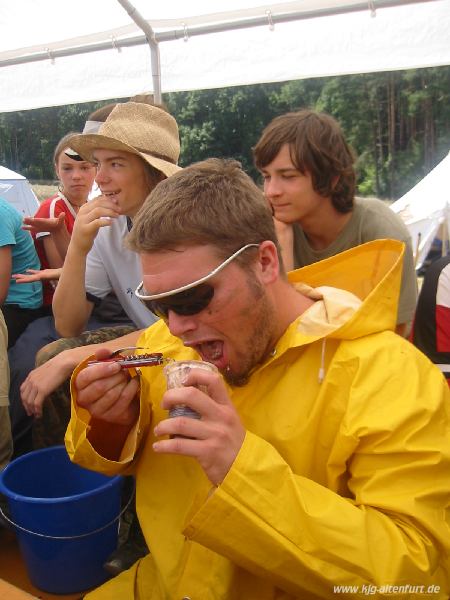 Christian isst mit Schutzbrille, Regenjacke und seinem Campinglöffel Sahnepudding