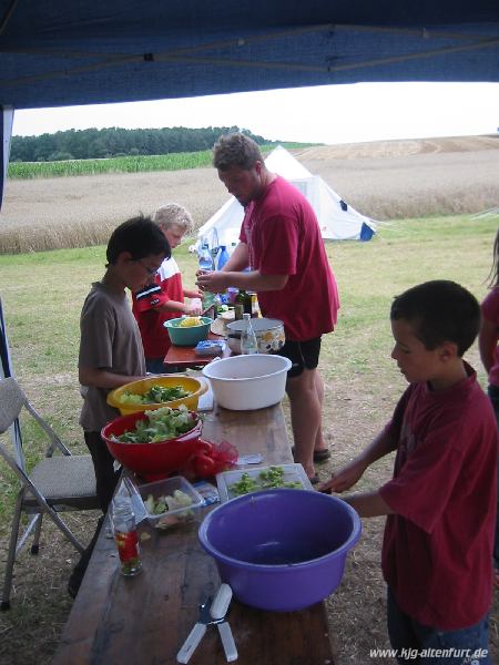 Christian und drei Teilnehmer bereiten verschiedene Salate für das Abendessen vor