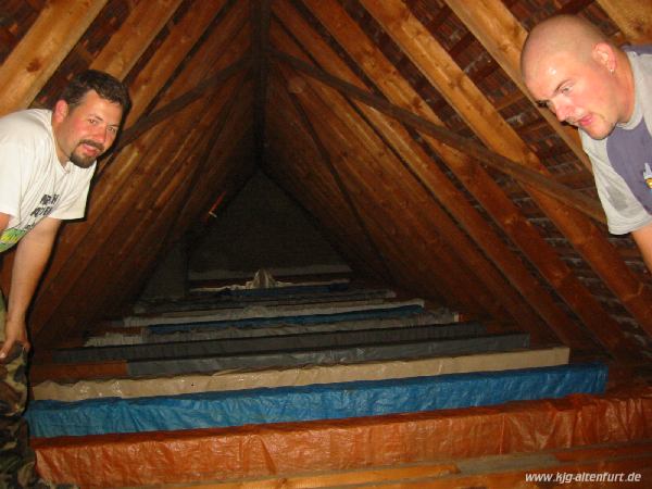 Martin und Markus stehen auf einem Balken im Dachboden, hinter ihnen Zelte und Zeltböden bis zu gegenüberliegenden Wand