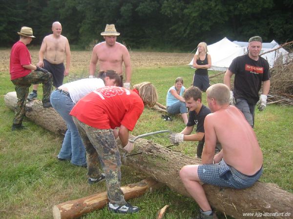 Teilnehmer und Leiter zersägen einen dicken Baumstamm