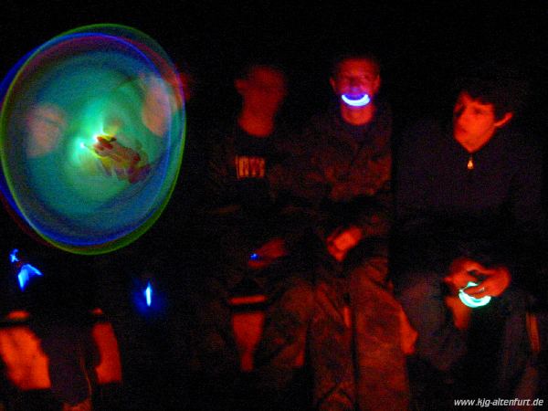 Die Teilnehmer malen mit leuchtenden Knicklichtern Muster in die Luft