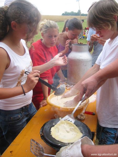 In einer Schüssel wird Teig angerührt, daneben wird auf dem Gaskocher ein Pfannkuchen gebacken